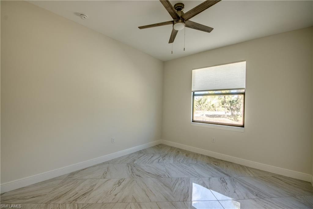 Spare room featuring a ceiling fan and light marble finish flooring