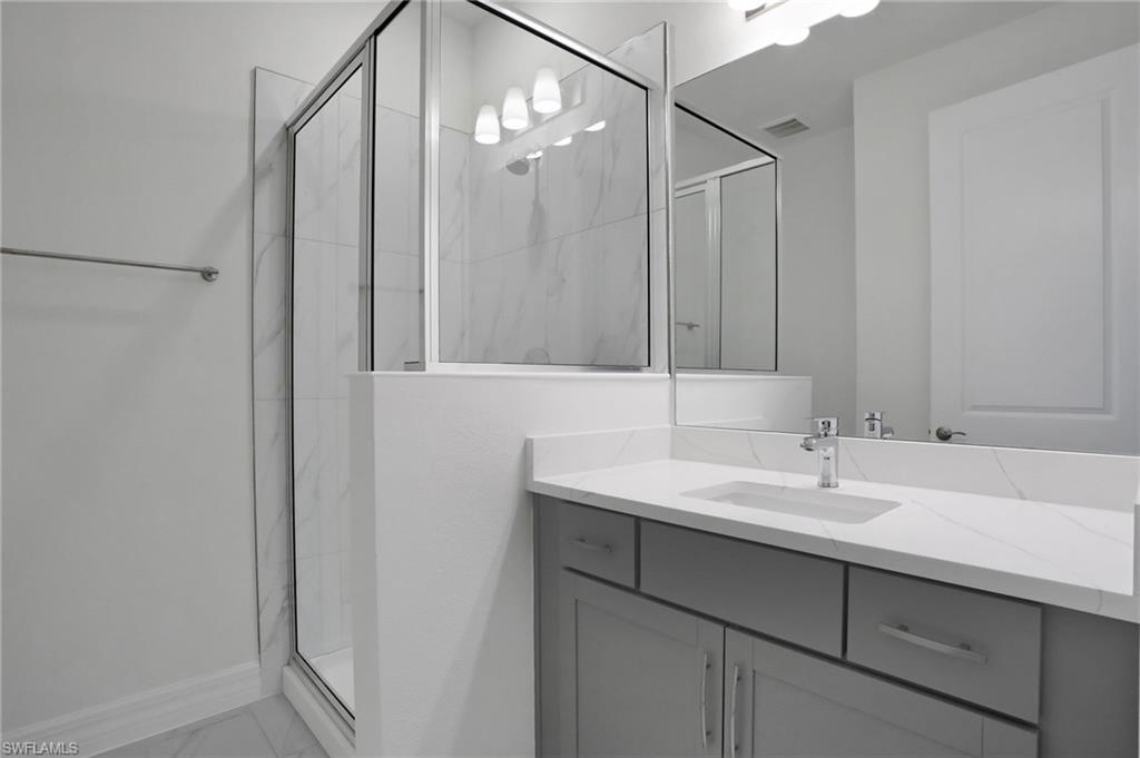 Full bathroom featuring a marble finish shower, vanity, and light marble finish floors