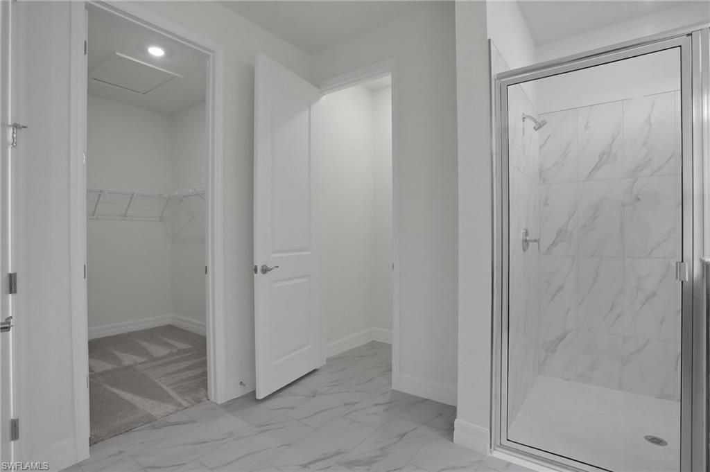 Full bathroom with light marble finish flooring, a marble finish shower, a walk in closet, and recessed lighting