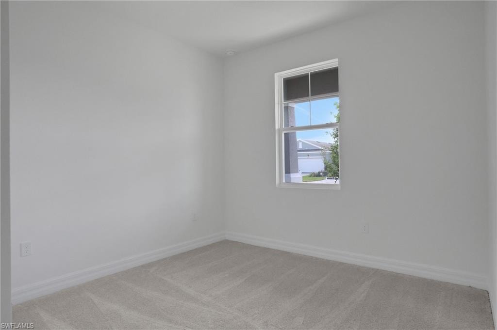Empty room featuring light carpet and baseboards