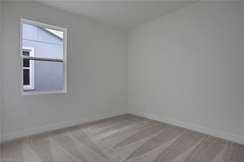 Empty room featuring light colored carpet and baseboards