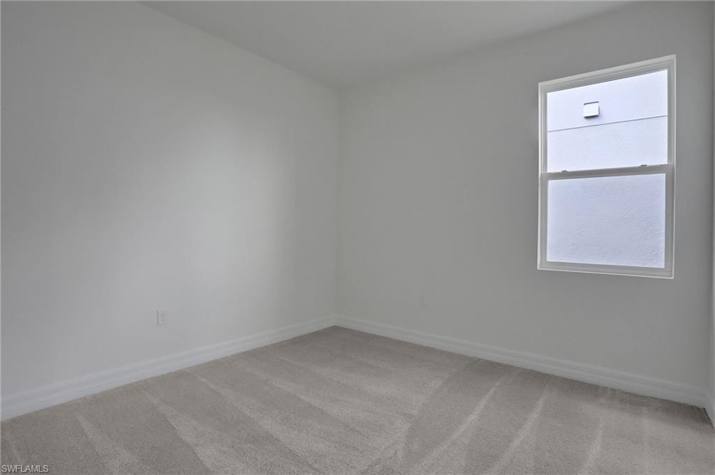 Unfurnished room featuring light carpet and baseboards