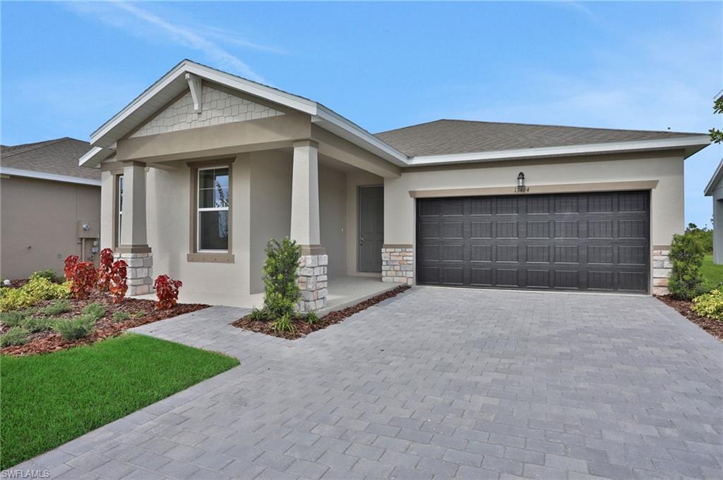 Craftsman-style house with stucco siding, stone siding, driveway, a porch, and an attached garage