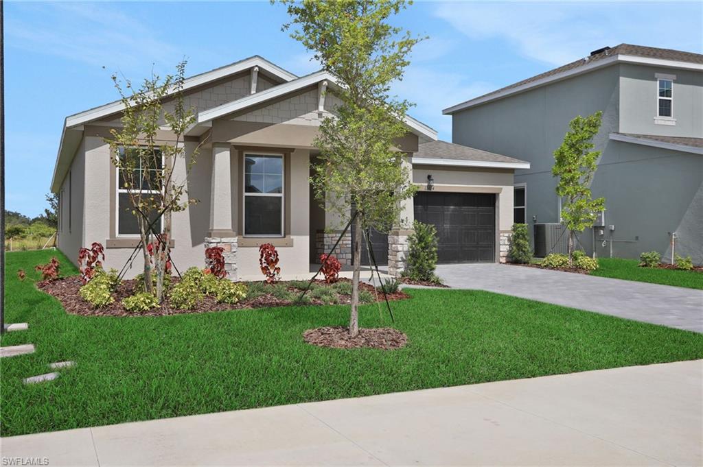View of front of property featuring a front yard, stucco siding, driveway, and a garage