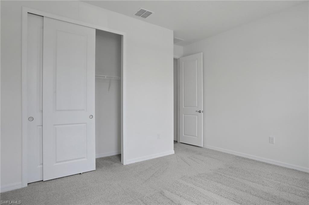 Unfurnished bedroom with light colored carpet and a closet