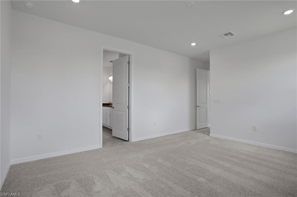Empty room with light colored carpet and recessed lighting
