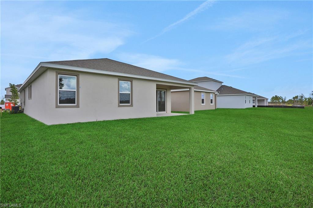 Rear view of property featuring a patio, a lawn, stucco siding, and a shingled roof