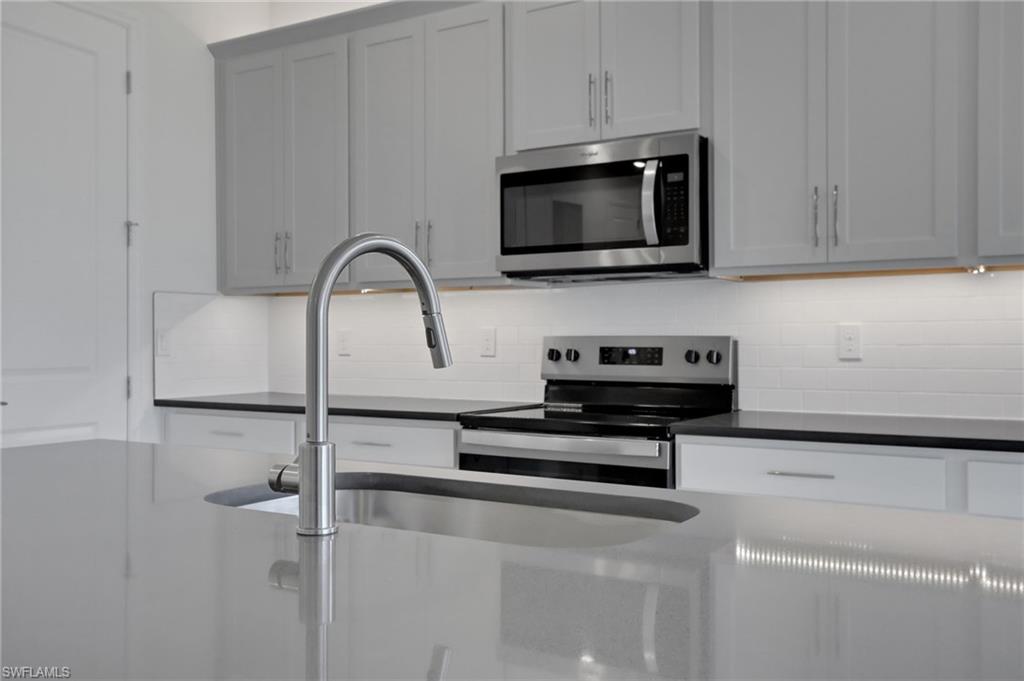 Kitchen with stainless steel appliances, tasteful backsplash, and dark stone counters
