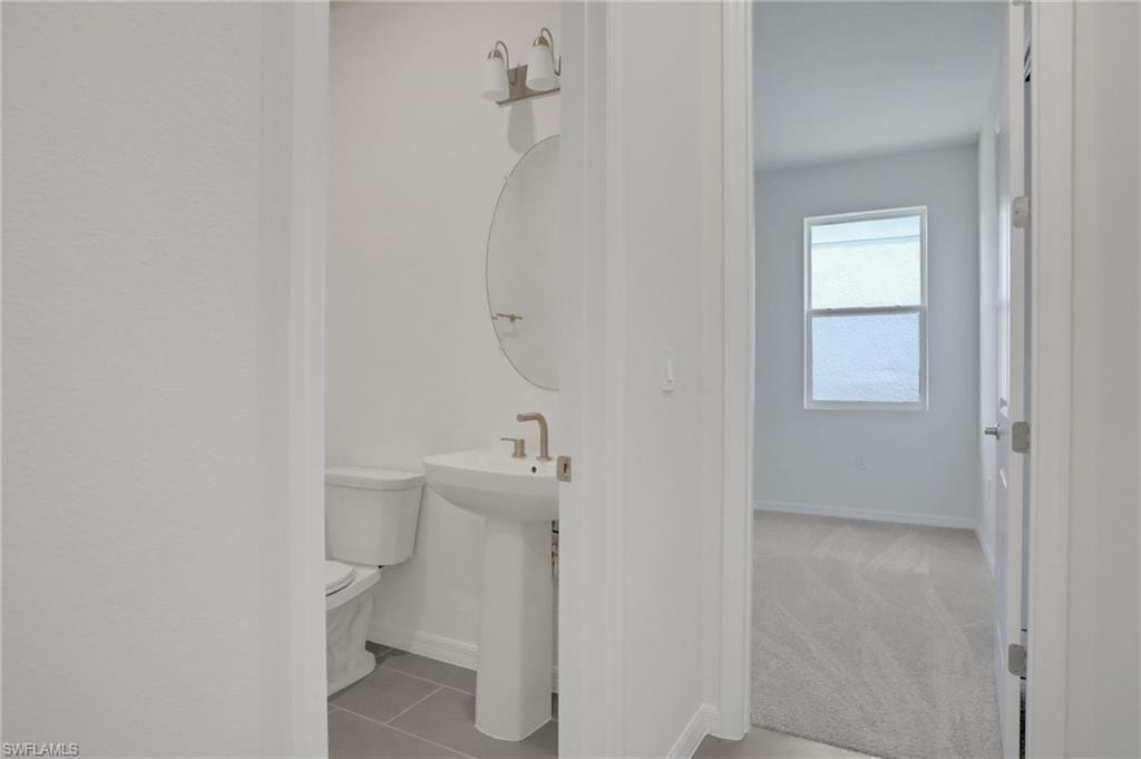 Half bath with toilet and light tile patterned floors