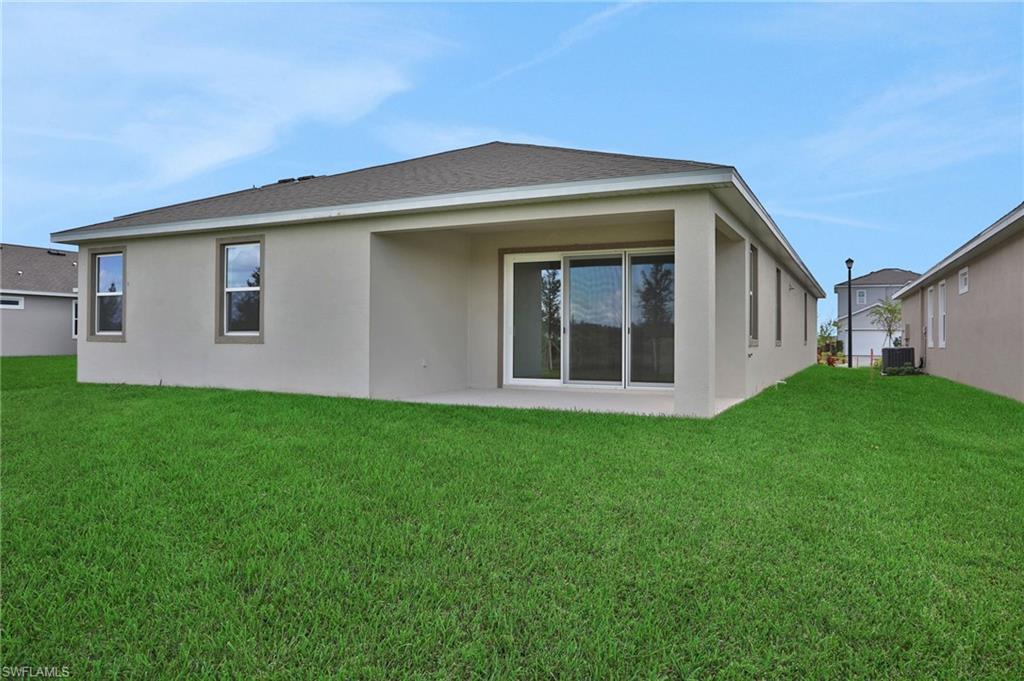 Rear view of house featuring a patio area, stucco siding, and a yard