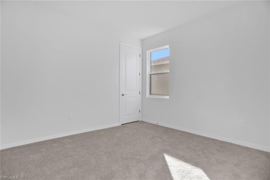 Empty room featuring carpet flooring and baseboards