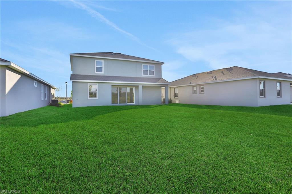 Back of house featuring stucco siding, a lawn, and a patio