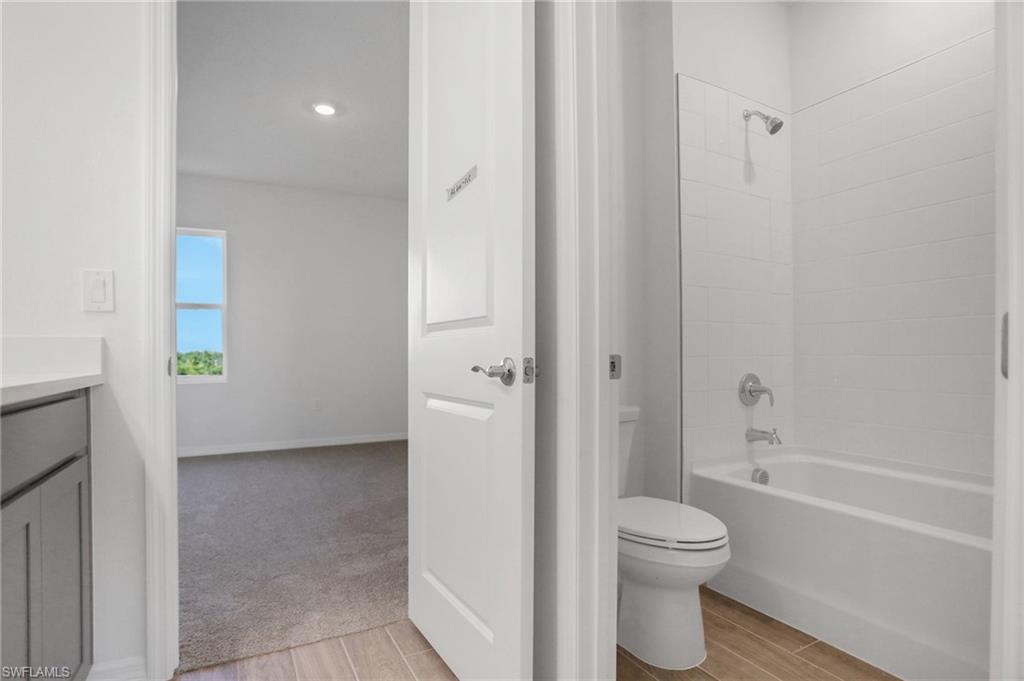 Full bathroom featuring vanity, tub / shower combination, wood finish floors, and recessed lighting