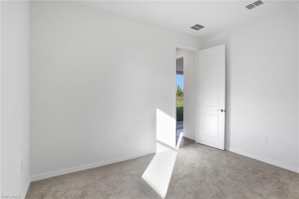 Empty room with light carpet and baseboards