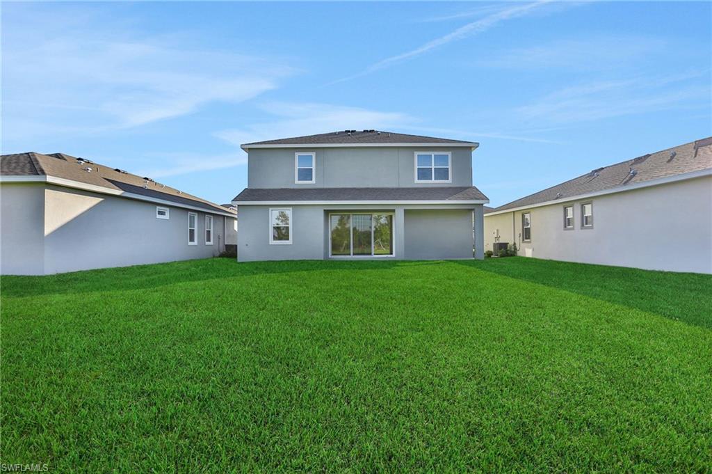 Back of house featuring stucco siding and a lawn