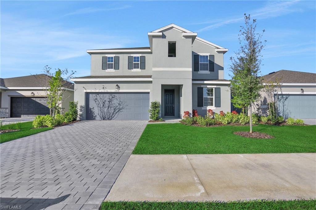 View of front of home featuring a garage, a front yard, stucco siding, and decorative driveway