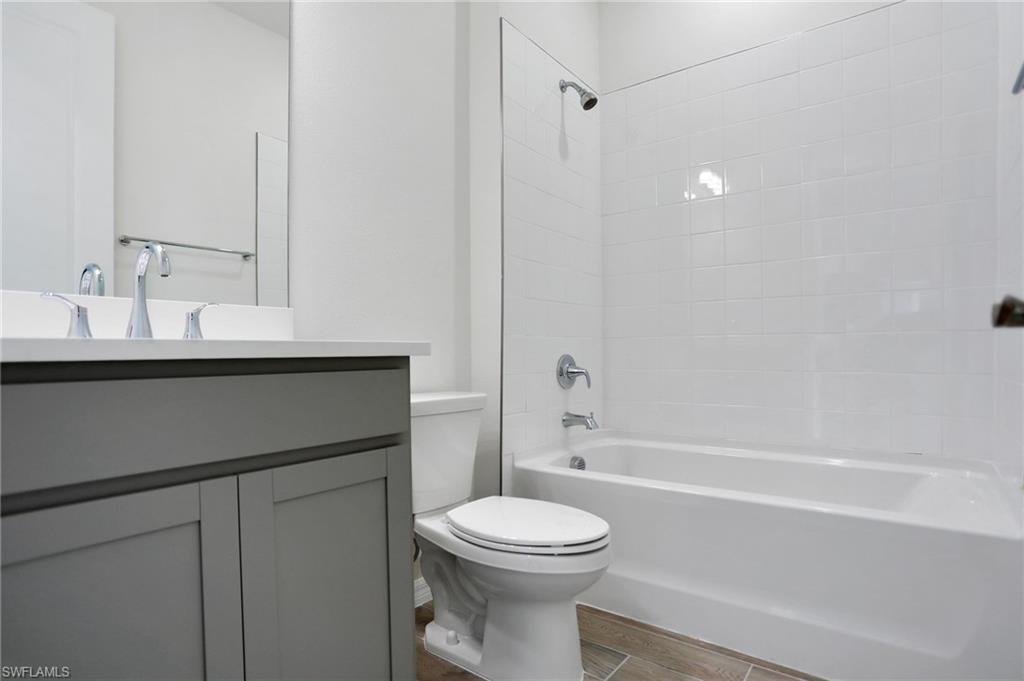 Full bathroom with washtub / shower combination, vanity, and wood tiled floors