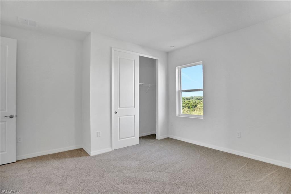 Unfurnished bedroom with light carpet and a closet