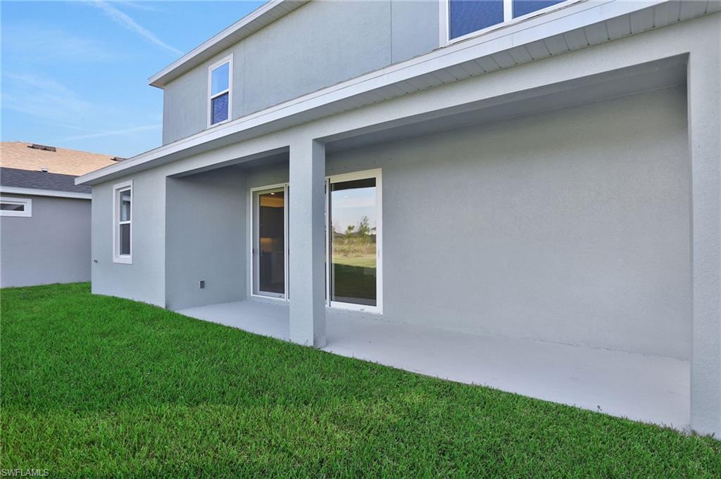 Back of house with stucco siding, a patio area, and a yard