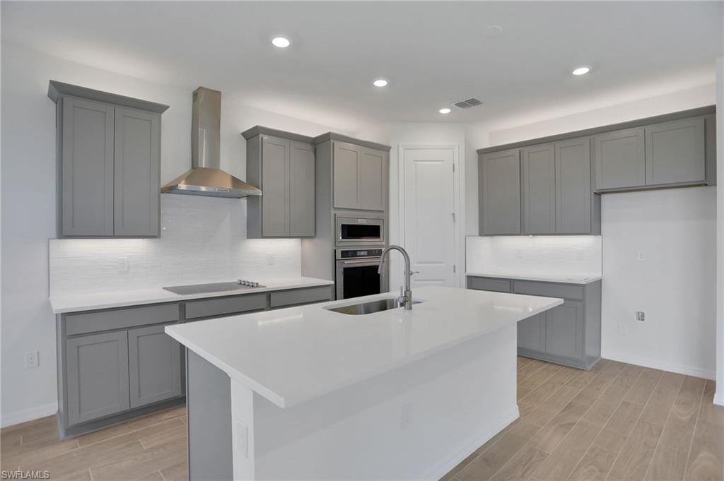 Kitchen with gray cabinetry, wood tiled floors, stainless steel appliances, and recessed lighting