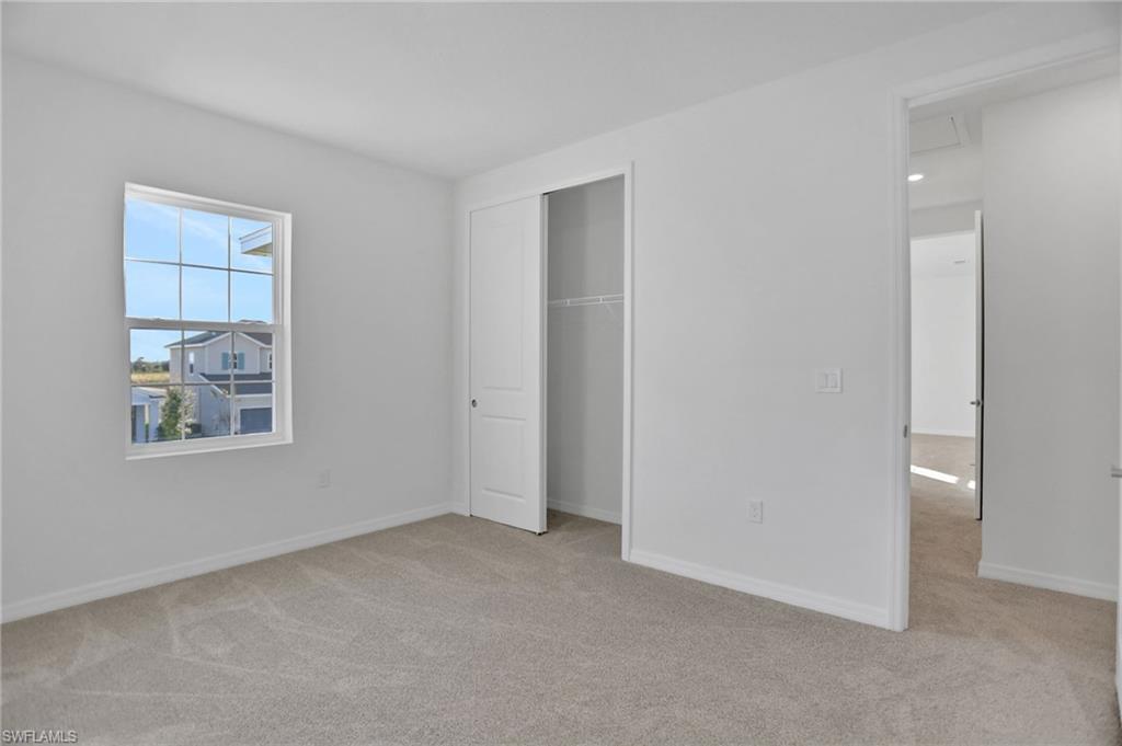Unfurnished bedroom with light carpet and a closet