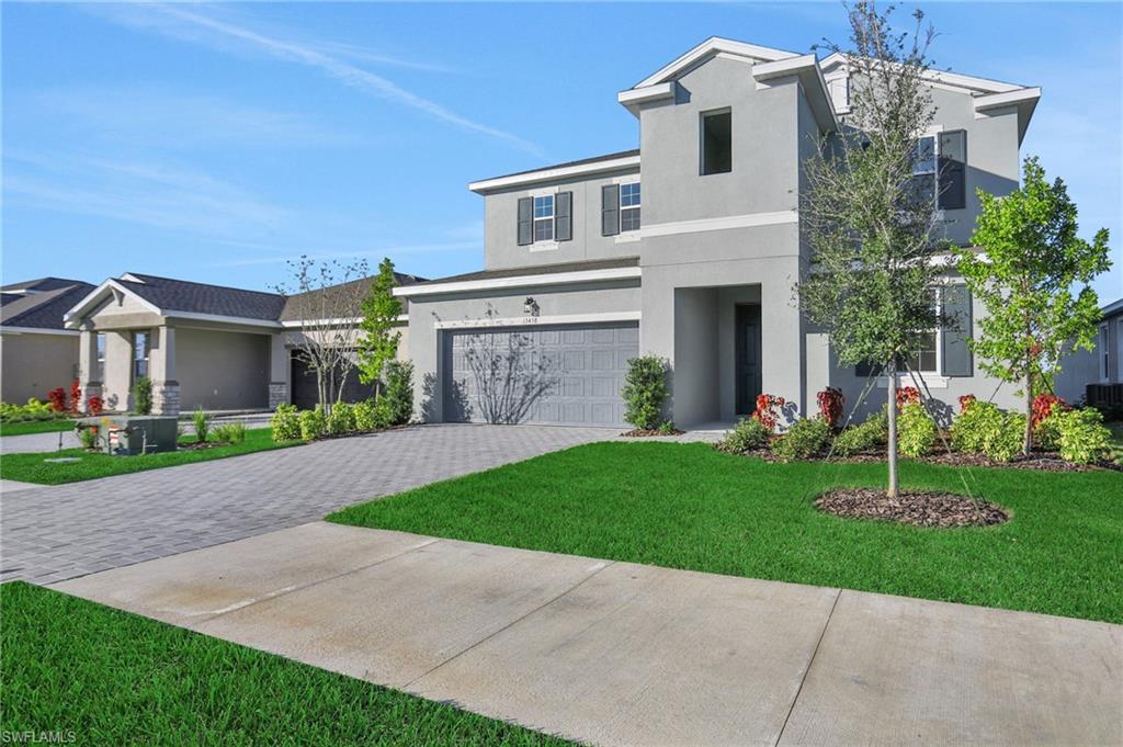 View of front of property featuring a garage, a front lawn, driveway, and stucco siding