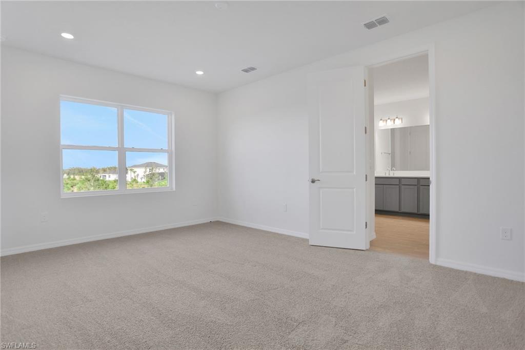 Unfurnished bedroom with light colored carpet, recessed lighting, and connected bathroom