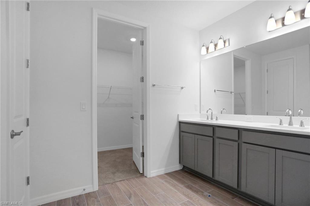 Bathroom with a spacious closet, double vanity, and wood finish floors