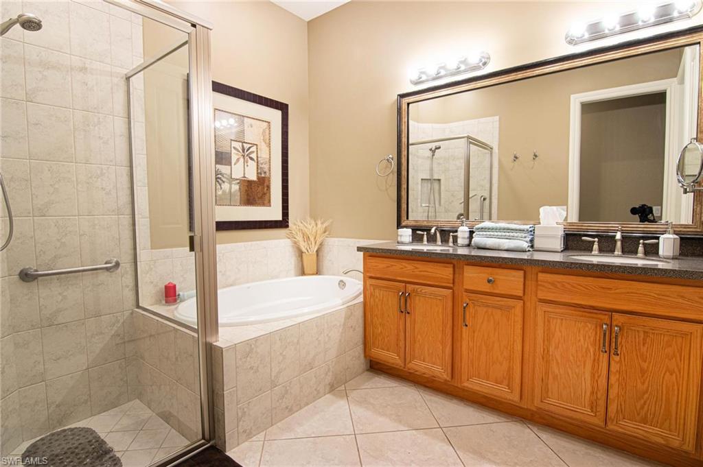 Bathroom with a shower stall, a garden tub, double vanity, and light tile patterned floors