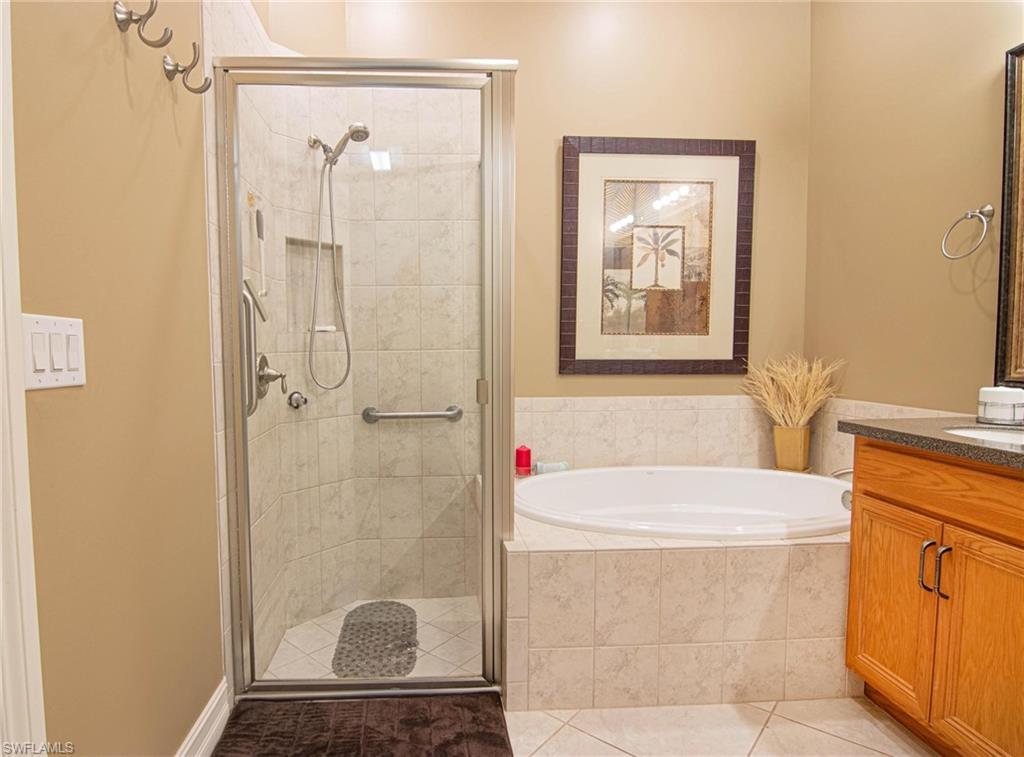 Bathroom featuring vanity, a garden tub, a stall shower, and light tile patterned floors