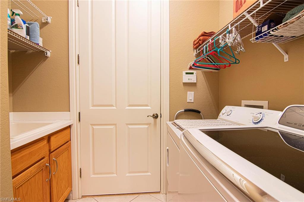 Laundry room featuring a textured wall, light tile patterned flooring, and washing machine and clothes dryer