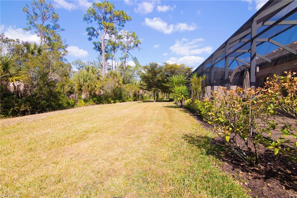 View of green lawn with a lanai and a sunroom