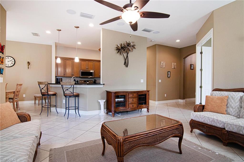 Living room with arched walkways, ceiling fan, recessed lighting, and light tile patterned floors