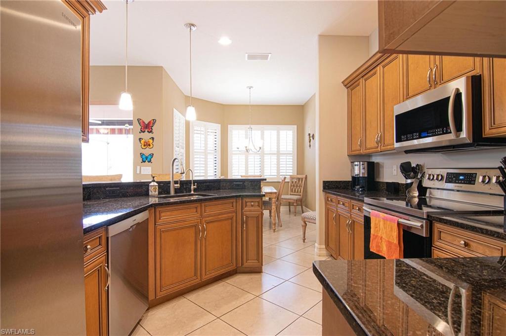 Kitchen with wood finish cabinetry, stainless steel appliances, and dark stone counters