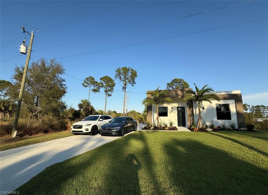View of front of home with stucco siding, a front lawn, and driveway