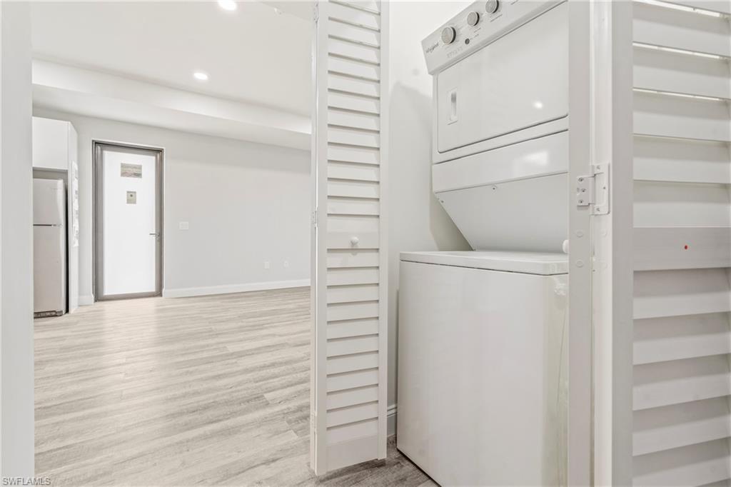 Laundry area featuring stacked washer / dryer, light wood-type flooring, and recessed lighting