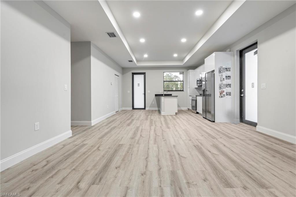 Unfurnished living room with a raised ceiling, light wood-style floors, and recessed lighting