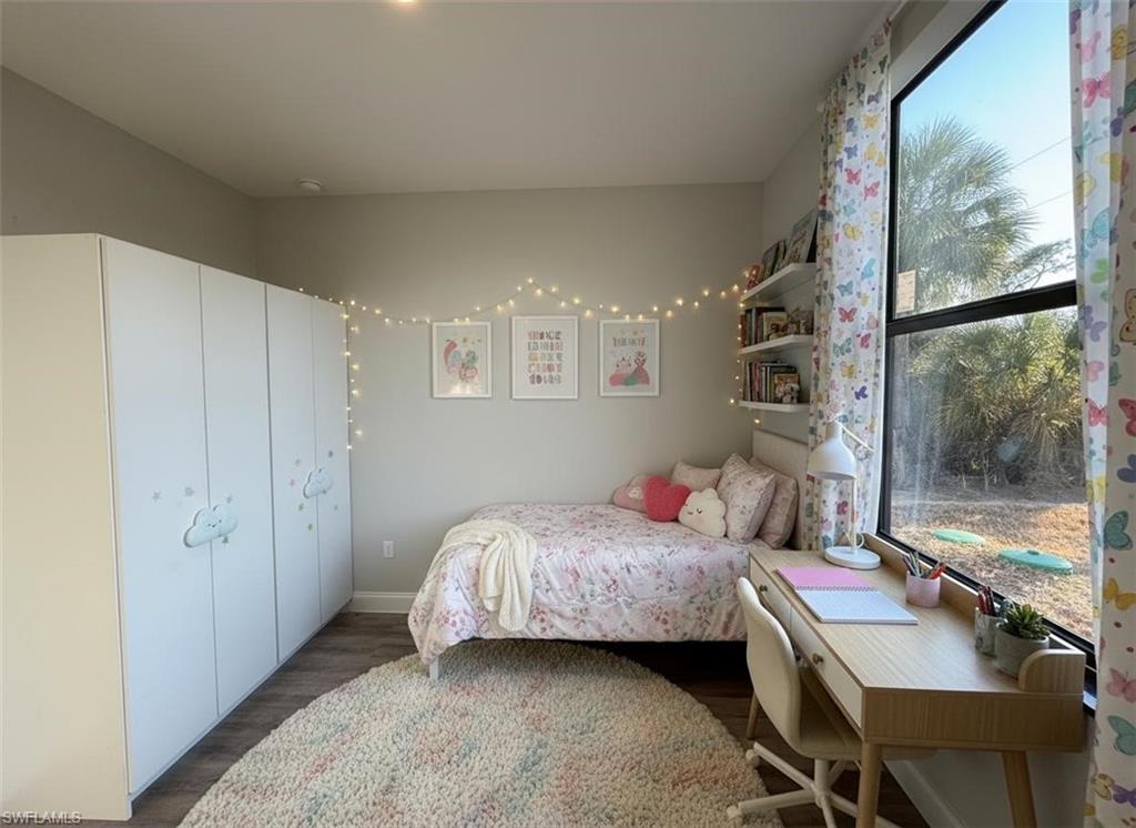 Bedroom with dark wood-style floors and baseboards