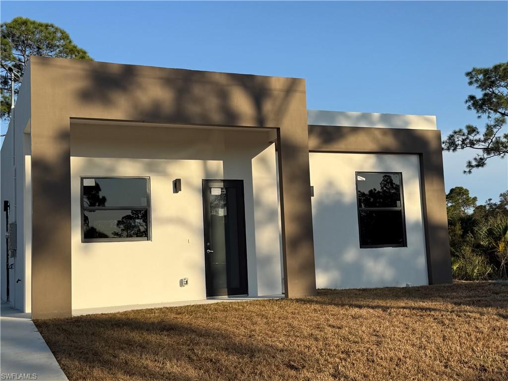 View of front of house featuring stucco siding and a front lawn