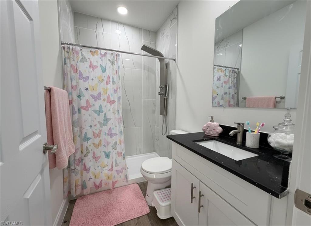 Bathroom featuring a stall shower, vanity, and dark wood finished floors