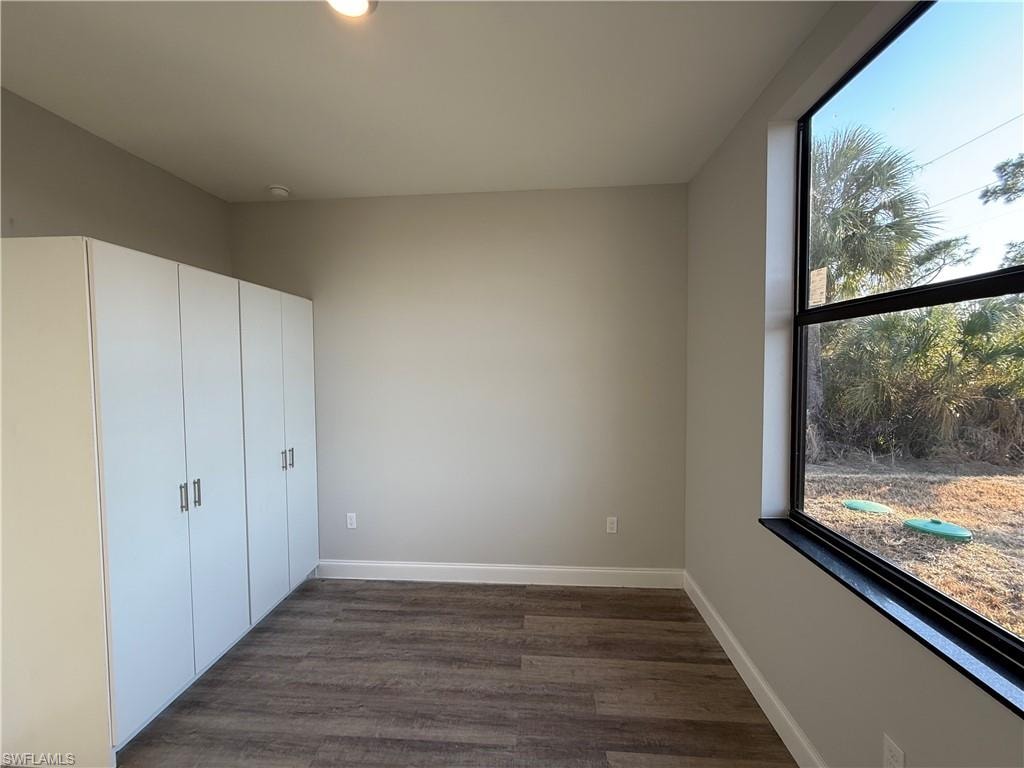 Unfurnished bedroom with baseboards and dark wood-style floors