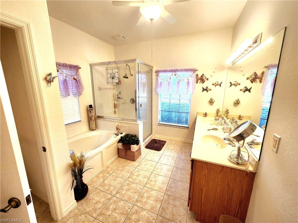 Bathroom with double vanity, a bath, a stall shower, a ceiling fan, and light tile patterned flooring