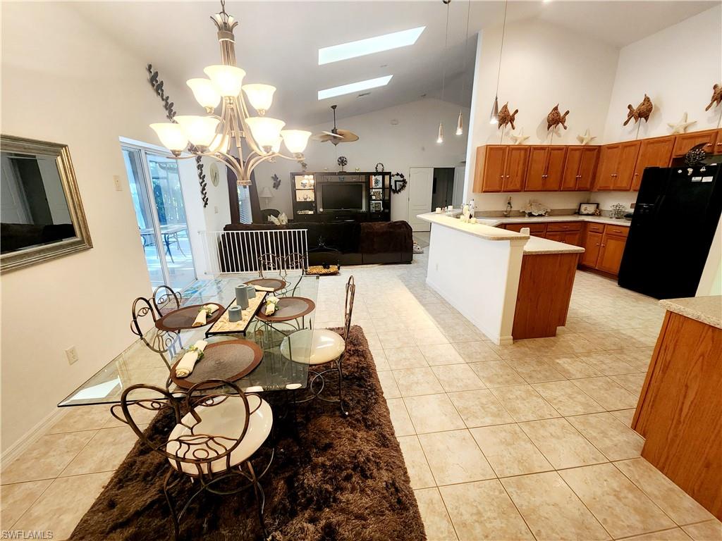 Kitchen with wood finish cabinetry, a skylight, black fridge with ice dispenser, open floor plan, and a peninsula