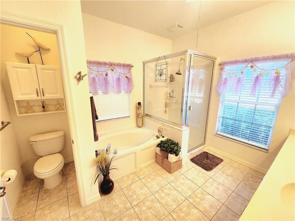 Bathroom with a stall shower, a garden tub, light tile patterned floors, and plenty of natural light