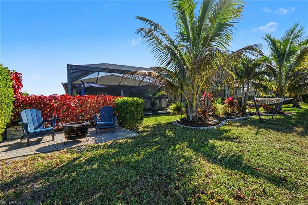 View of grassy yard featuring a patio, a sunroom, glass enclosure, and a fire pit