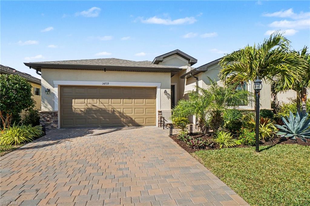 View of front of property with stucco siding, decorative driveway, and an attached garage