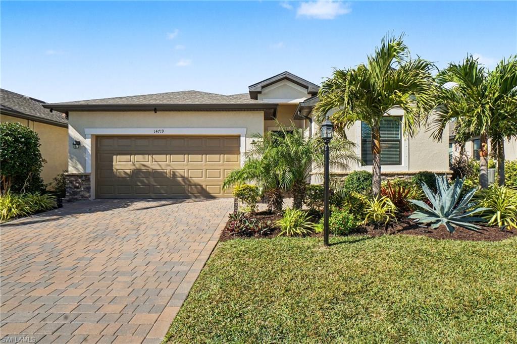 View of front of property with stucco siding, decorative driveway, and a front lawn
