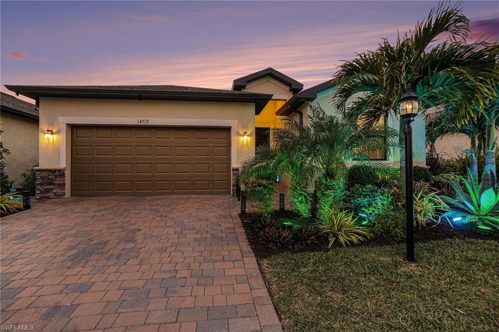 View of front of home with stone siding, stucco siding, decorative driveway, and a garage