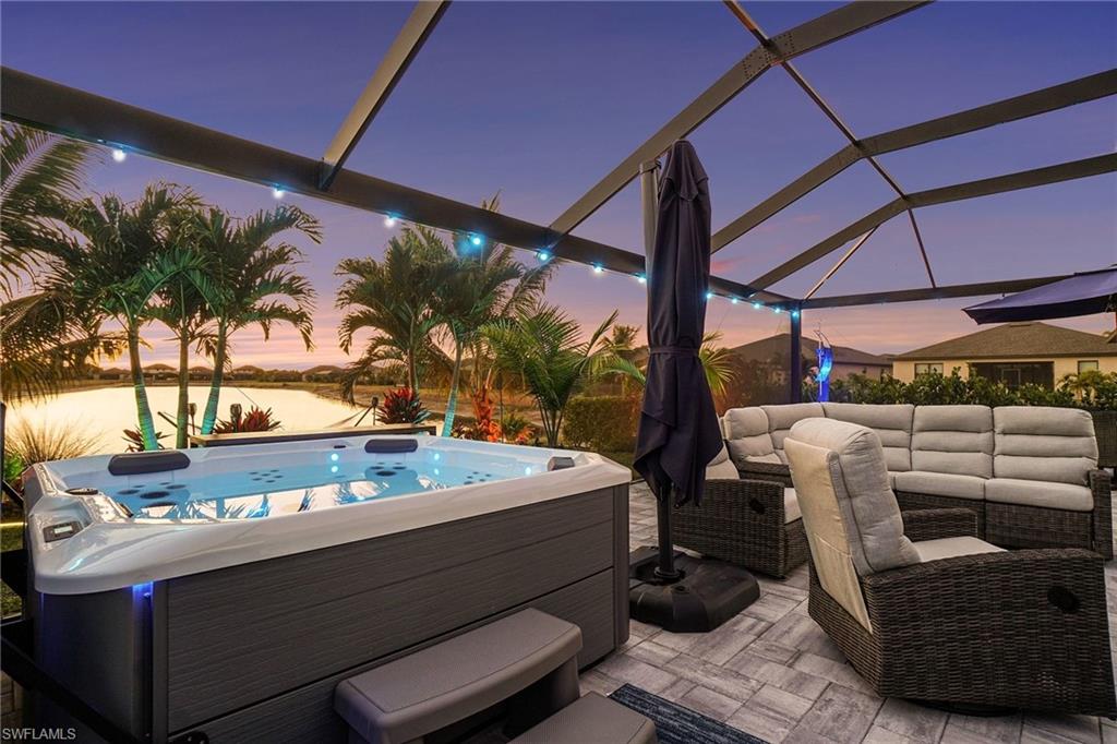 View of patio with an outdoor living space, a lanai, a water view, and a hot tub