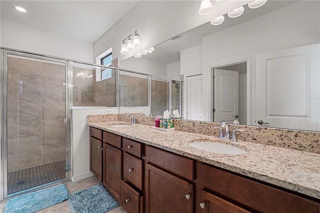Full bathroom featuring double vanity, a shower stall, and light tile patterned floors